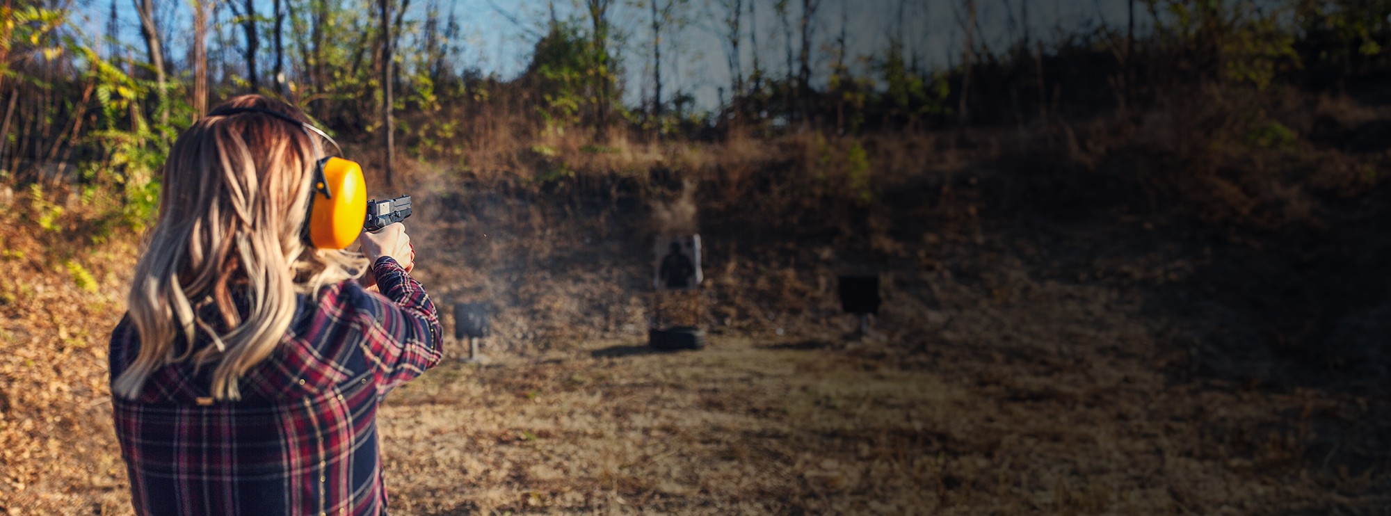 Wisconsin woman with hearing protection shooting a pistol at a target